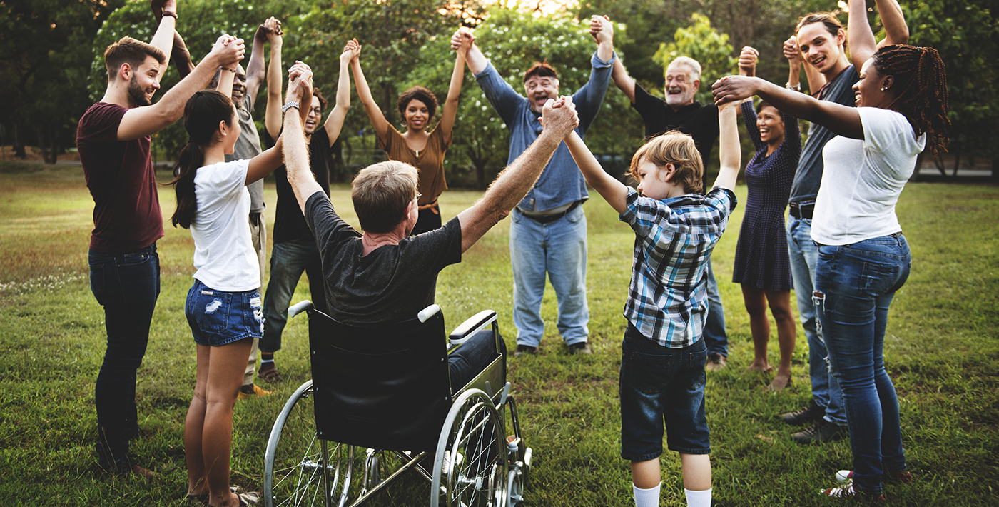 Inclusive community of people including wheelchair user joining hands